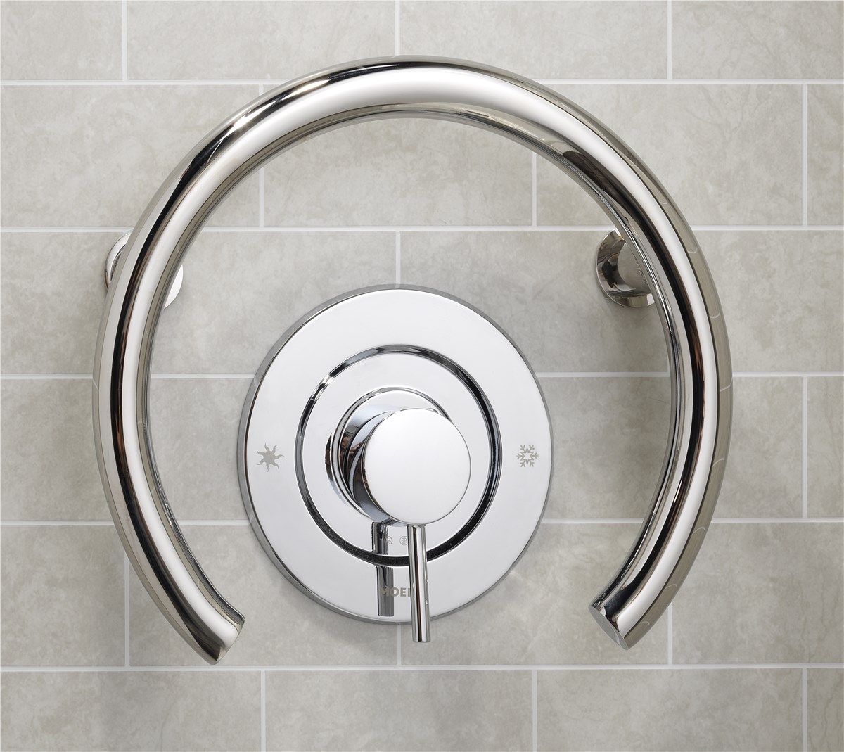 Chrome shower control with a circular handle and temperature indicators, mounted on a light gray tiled wall.