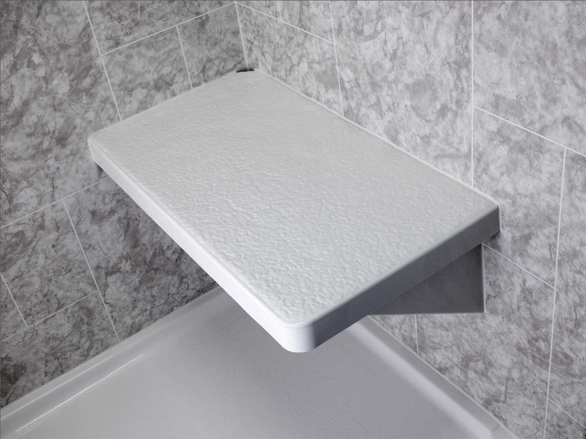 A white, rectangular, foldable shower seat is mounted on the corner wall of a shower with gray marble-patterned tiles.