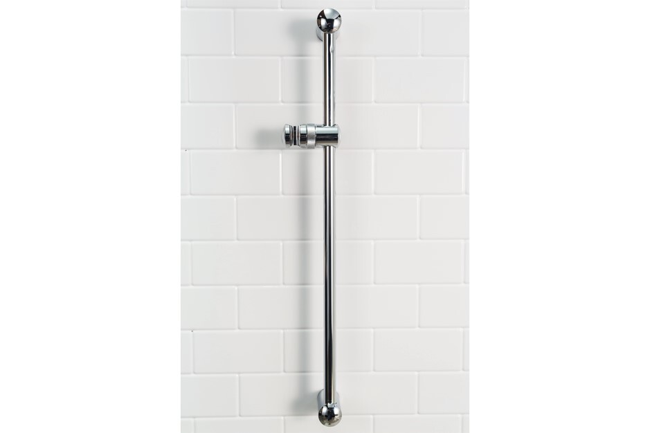 Chrome shower slide bar, mounted vertically, against white subway tile.