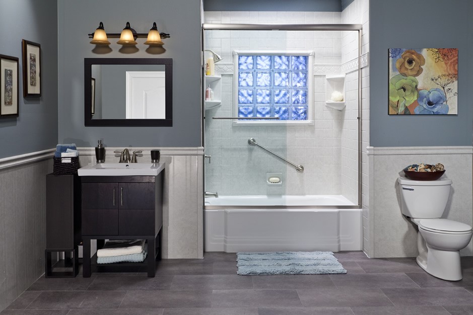 Bathroom with dark gray walls, a white tile shower with glass doors and a window of blue glass blocks, a dark wood vanity, and a toilet.