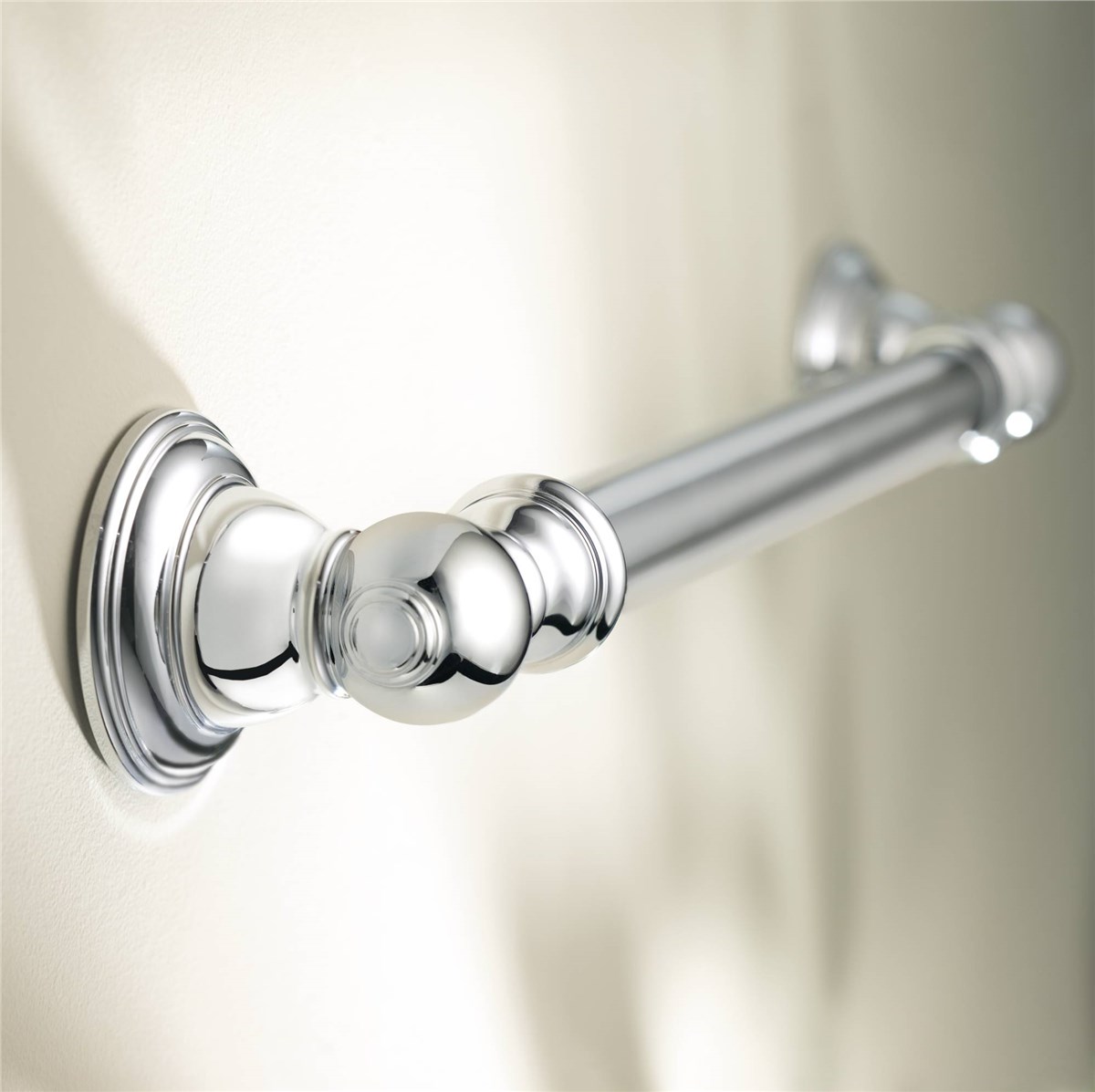 A close-up view of a polished chrome towel bar mounted on a light-colored wall, showing decorative round wall plates at each end.