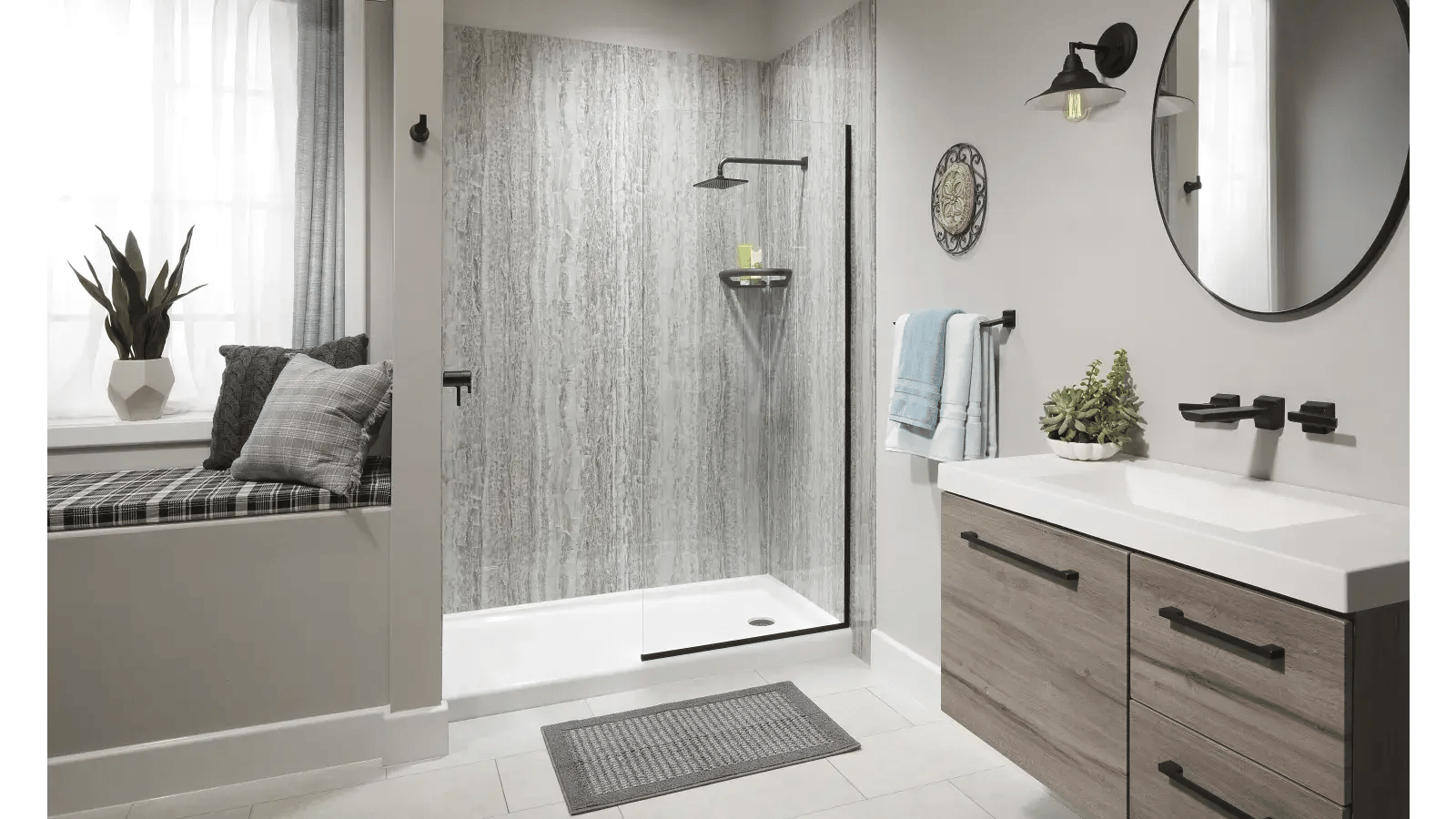 Modern bathroom with walk-in shower, floating vanity, round mirror, and window seat.