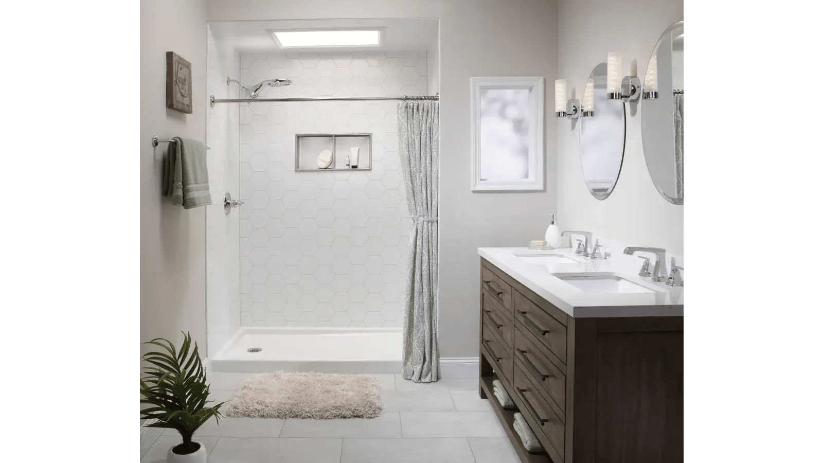 Bathroom featuring white tiled shower with built-in shelf, dual sink vanity with wood drawers and cabinet, and oval mirrors.