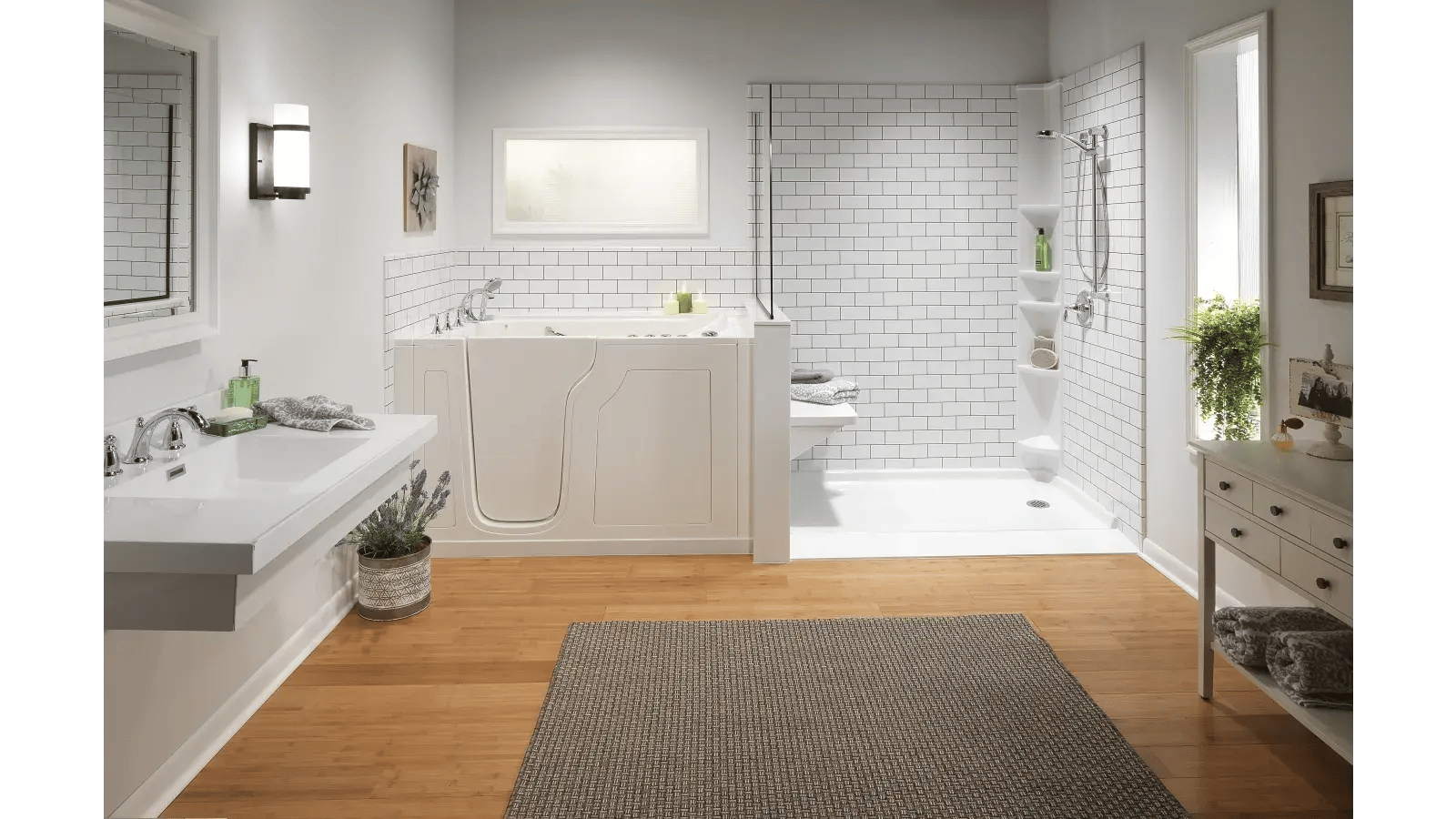 Bathroom featuring walk-in tub connected to a barrier-free shower with white subway tile, contrasted by light wood flooring and a gray rug.