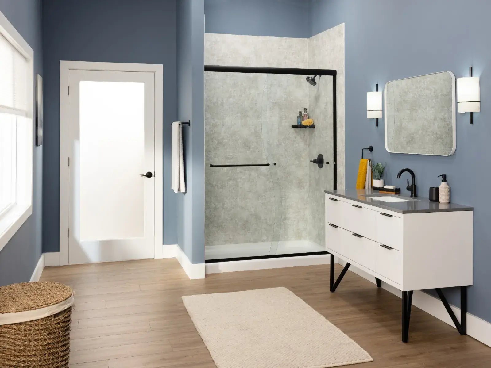A contemporary bathroom with light wood-look tile flooring, blue walls, a white vanity with black hardware, and a shower enclosure with a black frame.