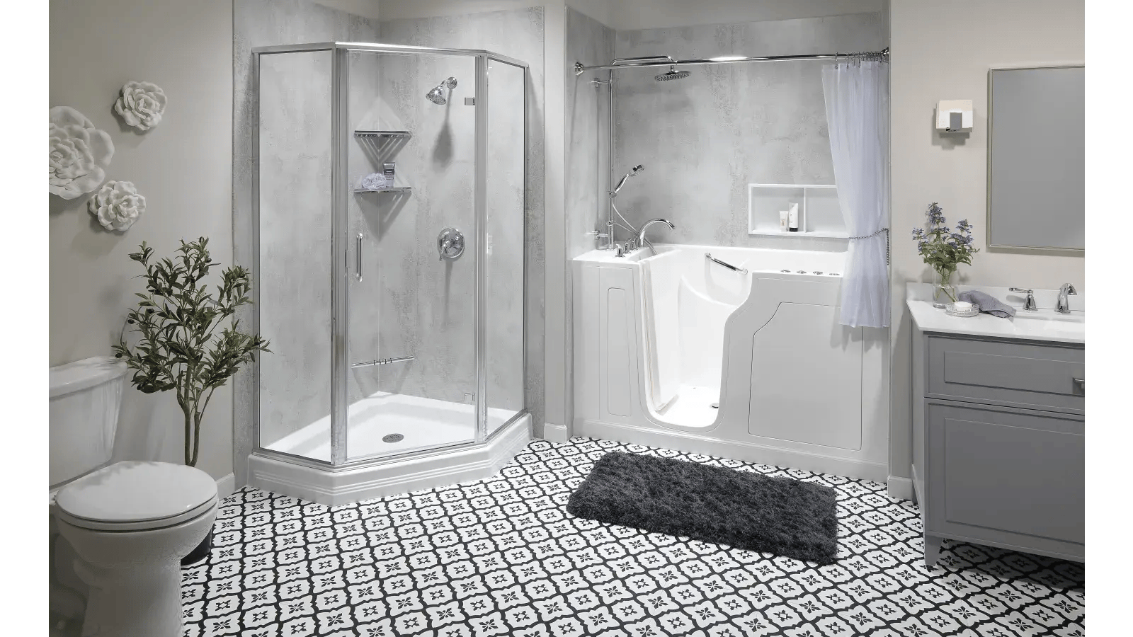 Bathroom featuring a walk-in tub with adjacent clear-walled shower, dark patterned floor tiles, gray vanity with light-colored countertop, and a gray shag rug.