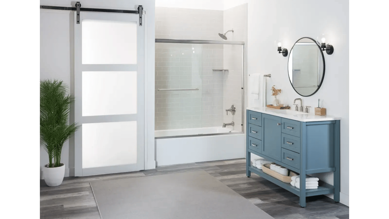 Bathroom with pale blue vanity, round mirror, and sliding barn door.