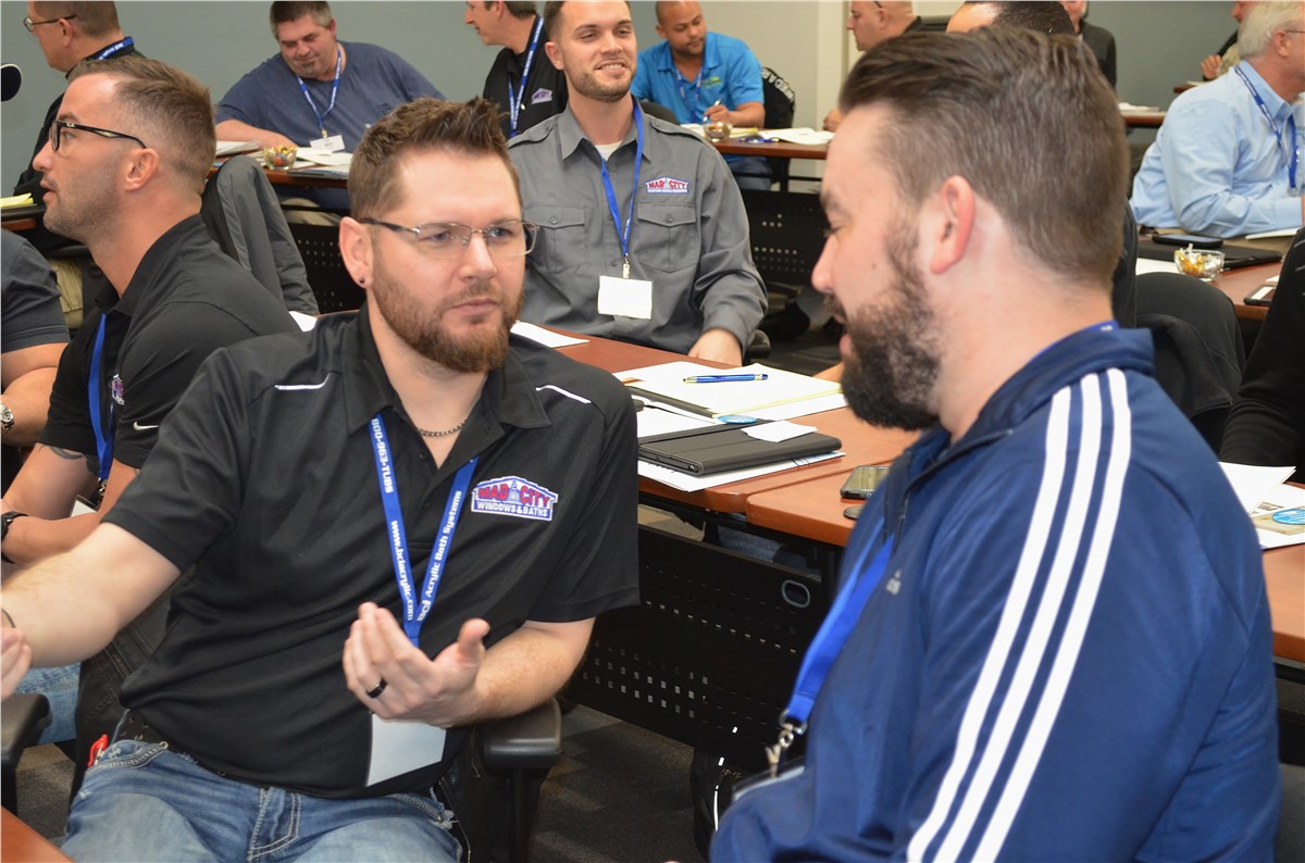 Man gesturing at screen showing custom spray foam base guide, holding a tablet.
