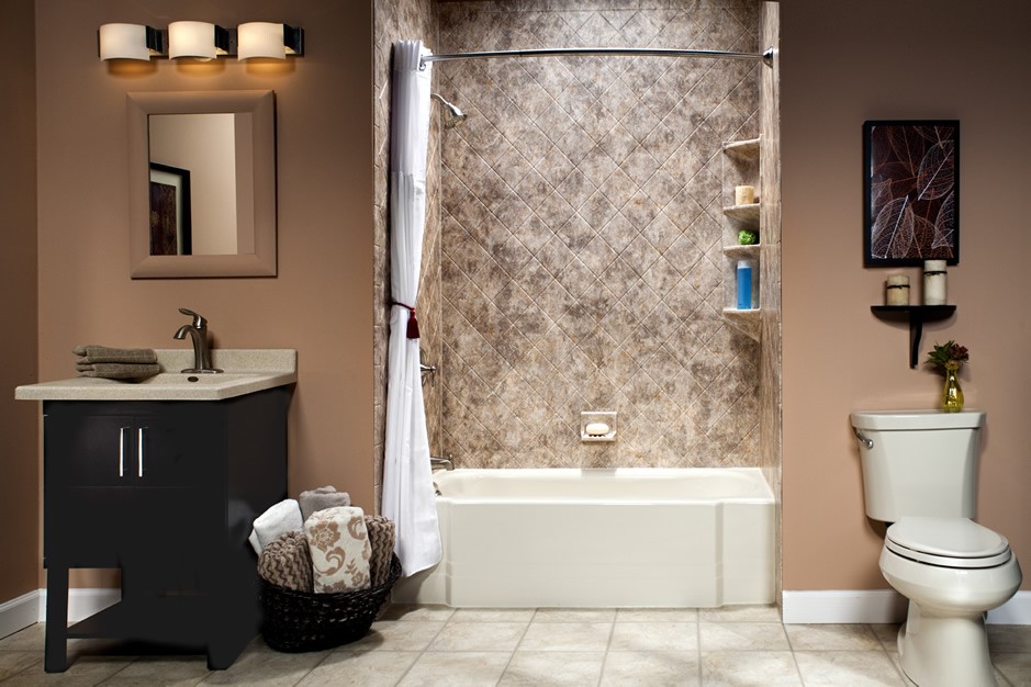 Bathroom featuring a beige-toned tiled floor and soft-brown walls, complete with a white toilet, dark-wooden vanity with a light countertop and silver faucet, and a bathtub with mottled-brown tile surround, accessorized with dark-wooden decorative items.